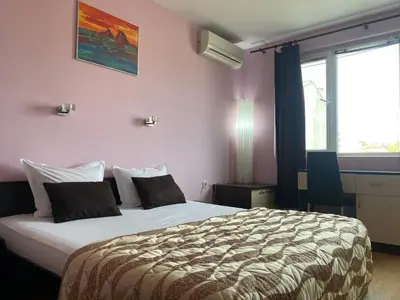 a bedroom with a large bed in a room with pink walls at Holidays apartment Bourgas in Burgas City