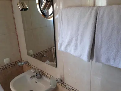 a bathroom with a sink and a mirror and towels at Family Hotel Hit in Kiten