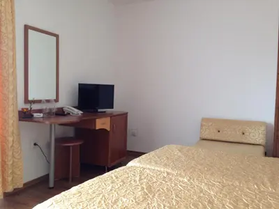 a bedroom with a bed and a desk with a mirror at Family Hotel Hit in Kiten