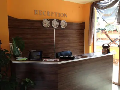 an office with a reception desk with clocks on the wall at Family Hotel Hit in Kiten