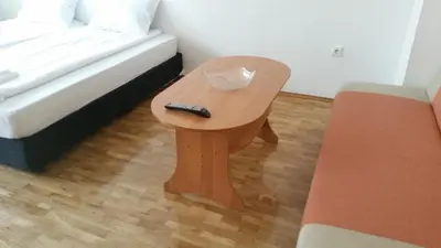 a remote control sitting on a wooden table next to a bed at 4U Apartment - Gurko in Burgas City