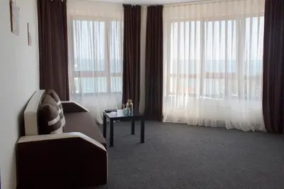 a living room with a couch and a table and windows at Lozenets View Hotel in Lozenets