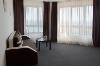 a living room with a couch and a table and windows at Lozenets View Hotel in Lozenets