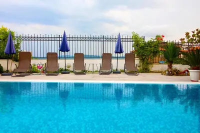a swimming pool with chairs and blue umbrellas at Luxury House on Buzhaka in Sozopol