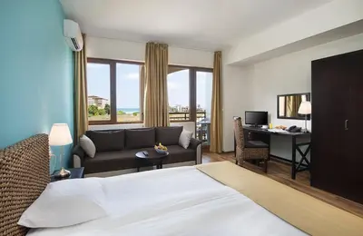 a hotel room with a bed and a couch and a desk at Sunrise All Suites Resort- All Inclusive in Obzor