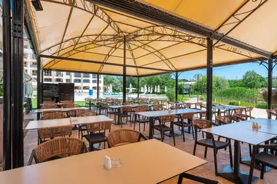 an empty restaurant with tables and chairs under a large umbrella at Sunrise All Suites Resort- All Inclusive in Obzor