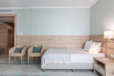 a bedroom with a bed and two chairs at Hotel Neptun Beach in Sunny Beach