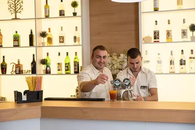 two men standing behind a bar with a drink at Hotel Laguna Park & Aqua Club - All Inclusive in Sunny Beach