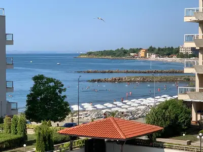 a view of a beach with umbrellas and the water at Apartments Helios in Pomorie