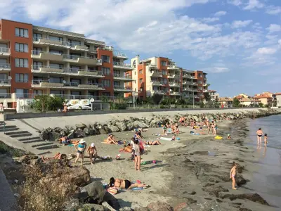 a group of people on a beach with buildings at Apartments Helios in Pomorie
