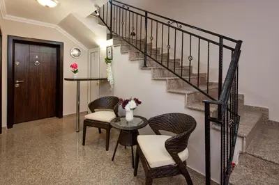 a hallway with a staircase with chairs and a table at Feniks Apartments in Nesebar