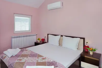 a bedroom with a large bed with white sheets and a window at Feniks Apartments in Nesebar