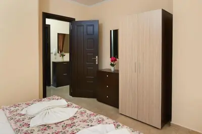 a bedroom with a bed with a dresser and a mirror at Feniks Apartments in Nesebar