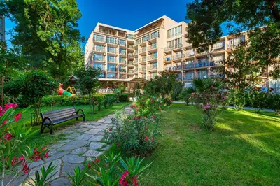 a park with a bench in front of a building at Hotel Riva Park - All Inclusive in Sunny Beach