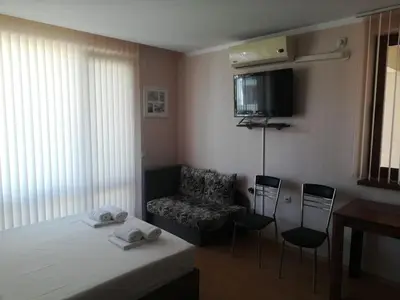 a bedroom with a bed and chairs and a tv at Sea View Apartment PRESTIGE FORT BEACH , PREMIER FORT BEACH in Sveti Vlas