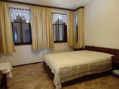 a bedroom with a large bed and two windows at Apartments Anita in Nesebar