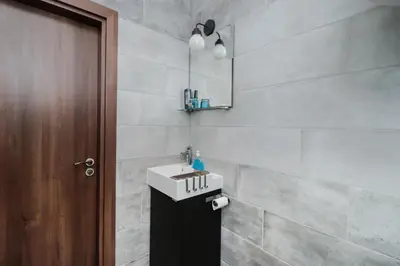 a bathroom with a white sink and a brown door at Sea Crib Apartment in Varna City