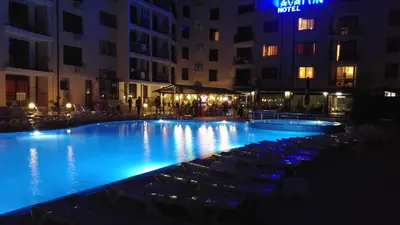 a large swimming pool at night with chairs and buildings at Avalon Apartament in Sunny Beach