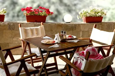 a wooden table and chairs on a patio with flowers at Fjord B&B in Sozopol