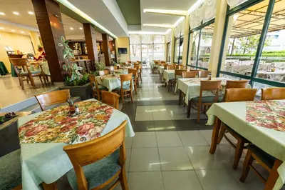 a dining room with tables and chairs and windows at Hotel Slavyanski in Sunny Beach