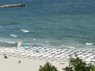 a beach with umbrellas and people in the water at Апартаменти Варна Саут на плажа - Varna South Apartments on the beach in Varna City