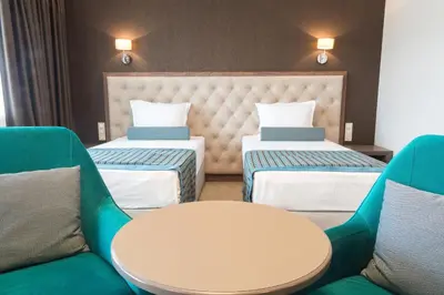a room with two beds and a table and chairs at Hotel Cherno More in Varna City