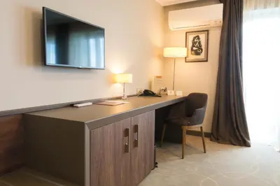 a hotel room with a desk with a television on the wall at Hotel Cherno More in Varna City
