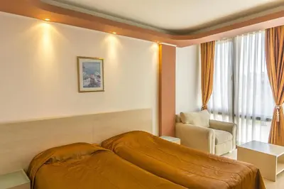 a bedroom with a bed and a chair and a window at Family Hotel Gold Pearl in Sunny Beach