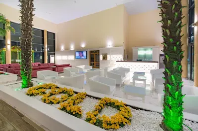 a lobby with a waiting area with white chairs and flowers at Hotel Perla Beach Luxury - All Inclusive & Free Beach Access in Primorsko