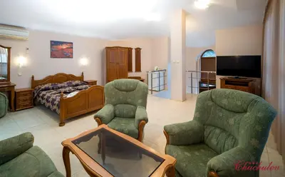 a living room with two chairs and a bed at Hotel Chuchulev in Sozopol