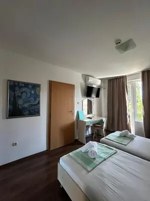 a hotel room with two beds and a desk at Family Hotel Magnolia, Sunny Beach in Sunny Beach