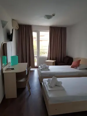 a hotel room with two beds and a desk at Family Hotel Magnolia, Sunny Beach in Sunny Beach