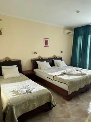 two beds in a room with blue curtains at Hotel Caesars Palace in Sunny Beach