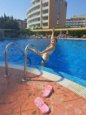 a little girl in a swimming pool with pink flip flops at Hotel Caesars Palace in Sunny Beach