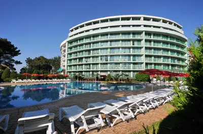 a large building with white lounge chairs and a pool at Hotel Caesars Palace in Sunny Beach