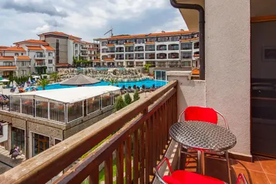 a balcony with a table and chairs and a swimming pool at Edmond Apartment-Highspeed-Internet-Free! in Aheloy
