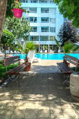 two park benches sitting next to a swimming pool at Yassen Holiday Village in Sunny Beach