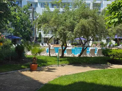 a resort with a swimming pool with chairs and trees at Yassen Holiday Village in Sunny Beach