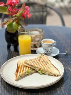 a sandwich on a plate on a table with a glass of orange juice at Guest House Palazzo in Byala