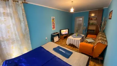 a blue room with a bed and a table at Аria B&B in Burgas City
