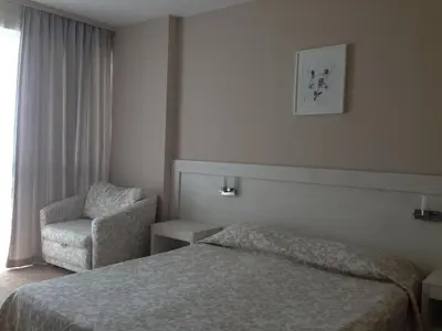 a hotel room with a bed and a chair at Sineva Beach Hotel - All Inclusive in Sveti Vlas