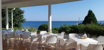 a group of tables and chairs with the ocean in the background at Sineva Beach Hotel - All Inclusive in Sveti Vlas