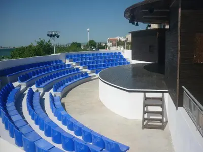 a stage with blue plastic chairs and a ladder at Sineva Beach Hotel - All Inclusive in Sveti Vlas