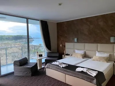 a bedroom with a large bed and a large window at Hotel Kamenec in Kiten