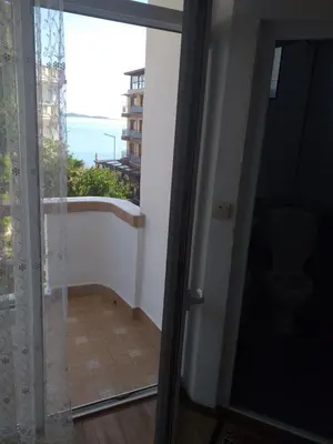 a door to a balcony with a view of the ocean at Primorsko Apartments in Primorsko
