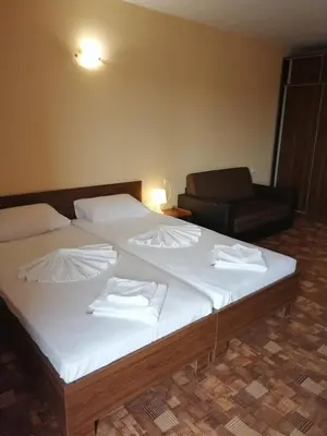 a bedroom with two beds and a chair at Hotel Sapphire in Primorsko