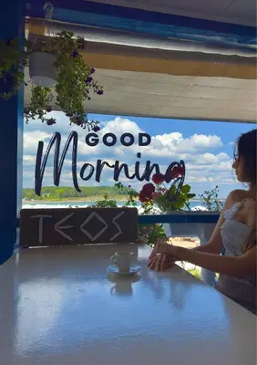 a woman sitting at a table with a cup of coffee at Family Hotel Teos in Kiten