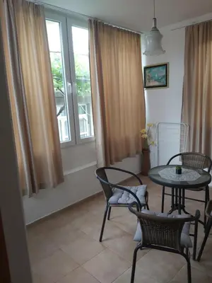 a living room with a table and chairs and windows at Kyshta za Gosti Dari Rumi 1 in Sozopol