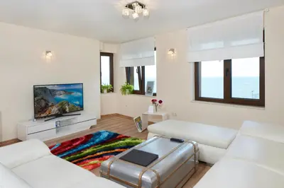 a living room with white furniture and a flat screen tv at Villa Elea in Nesebar
