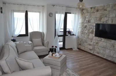 a living room with white furniture and a stone wall at Villa Elea in Nesebar